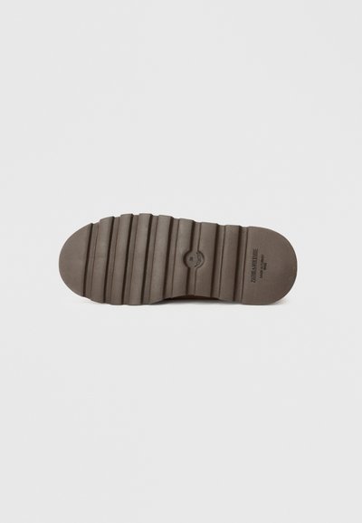 Sola de sapato de borracha castanha com canais horizontais e ponta arredondada, apresentando uma marca em relevo e uma superfície texturizada para maior tração.