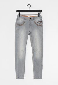 Ljust grå jeans med en åtsittande design, dekorativa fickdetaljer och subtila blekningar. Har dragkedja och knappstängning.