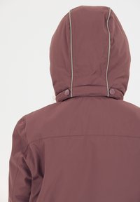 Bordeaux jakke med høj krave og hætte, med grå stikninger og to trykknapper bagpå. Glat, vandafvisende stof.