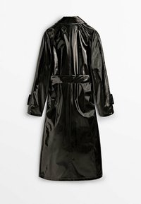 Long trench-coat en vinyle noir brillant, manches longues et ceinture à la taille, présenté de dos sur un fond uni.