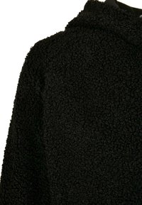 Zwarte fleece hoodie met een gestructureerd, pluizig oppervlak. Heeft een capuchon, lange mouwen en een overall relaxte pasvorm.