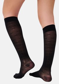 Schwarze knielange Socken mit transparenter Textur, die ein Punktemuster und ein festes schwarzes Band am oberen Rand aufweisen. Offene Zehen für zusätzlichen Komfort.