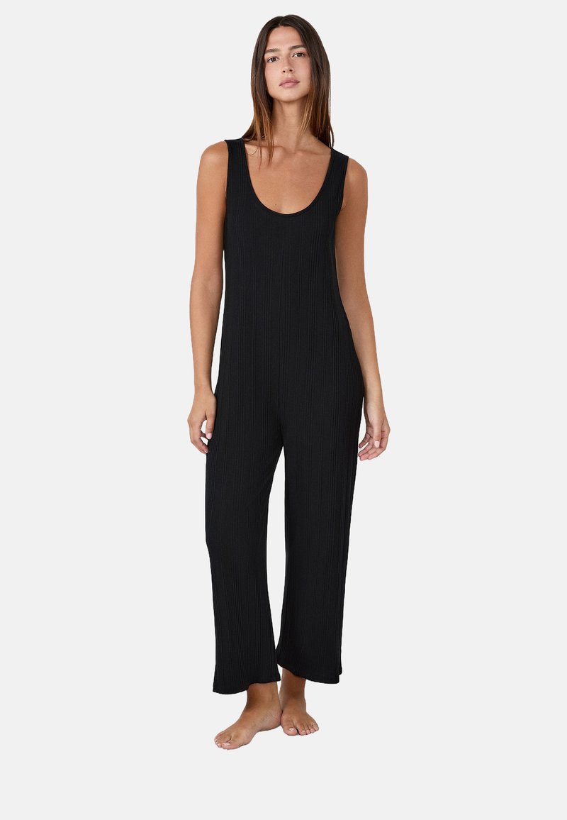 Mono negro con acanalado, escote de barco, diseño sin mangas, piernas amplias y un corte relajado. Fabricado en un material suave y elástico.