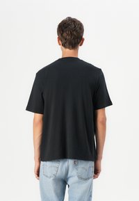 Sort bomuld t-shirt med korte ærmer, rund hals og en afslappet pasform, parret med lyseblå denim jeans. Simpel og uornamenteret design.