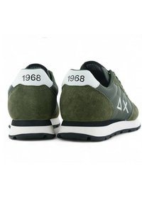 Sneaker verde oliva con tomaia in suede, caratterizzate da accenti bianchi e il numero "1968" sul tallone. Suola in gomma nera con design classico.
