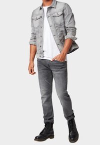 Grå denimjacka med bröstfickor, vit t-shirt, grå jeans och svarta kängor. Outfiten har en avslappnad lagerlook.