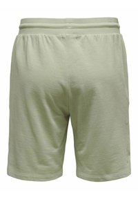 Pantalones cortos de algodón verde claro con una cinturilla elástica, que presentan una textura suave y un corte recto, terminando justo por encima de la rodilla.