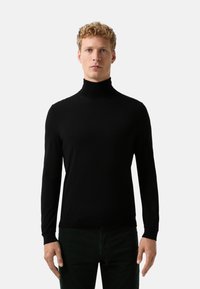 Schwarzer Rollkragenpullover aus weichem Material. Hat lange Ärmel und ein tailliertes Design, mit einer glatten Textur und ohne Muster.