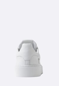 Sneaker bianco in pelle con texture liscia, tacco arrotondato, cuciture minime e suola in gomma piatta. Vista posteriore senza marchi visibili.