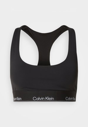 Czarny stanik sportowy z dekoltem w kształcie łódki i konstrukcją typu racerback. Posiada szeroki czarny pas z białym logo "Calvin Klein". Gładka tekstura.