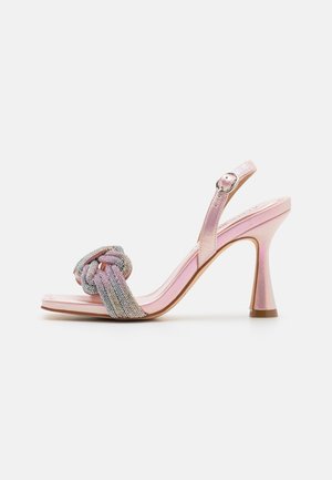 Rosa High Heels Sandalen mit glänzendem Finish, ausgestattet mit einem geknoteten, mehrfarbigen Riemen, der mit metallischen Akzenten verziert ist.