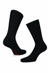 Czarne skarpetki w małe czerwone kropki, wykonane z miękkiego materiału, z bezszwowym palcem i czerwonym logo na podeszwie.