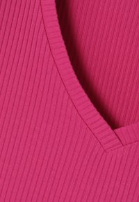 Top aderente in tessuto a coste rosa con scollatura a V. La texture è morbida e presenta righe verticali che mettono in evidenza l'elasticità.