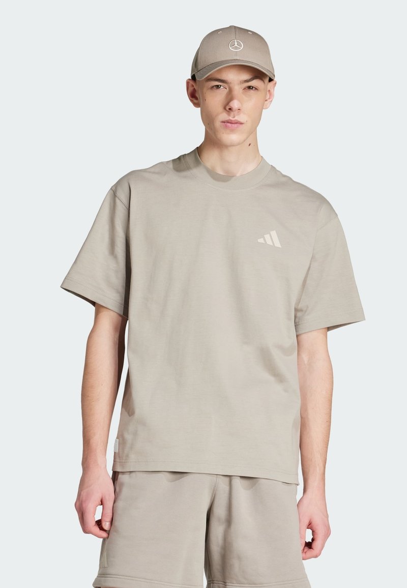 Beżowy T-shirt z okrągłym dekoltem, wykonany z miękkiego materiału, posiadający krótkie rękawy i subtelne logo w diagonalne paski na piersi. W komplecie z beżowymi szortami.