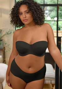 Soutien-gorge noir sans bretelles avec armatures et culotte taille haute assortie. Texture lisse, design structuré et détails de couture minimalistes.