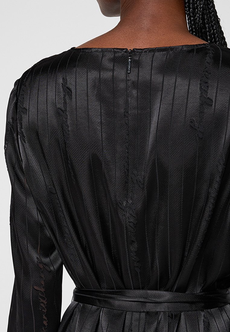 Černé saténové šaty se spodními jemnými vertikálními pruhy, zipem na zadní straně a odpovídajícím páskem v oblasti pasu pro strukturální přizpůsobení.