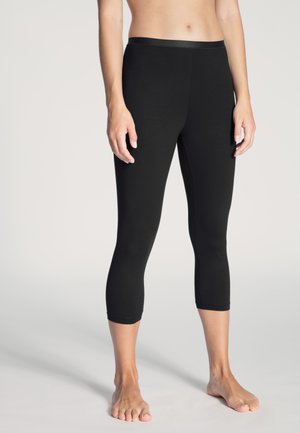 Zwarte capri-legging gemaakt van rekbaar materiaal, met een hoge tailleband en een aansluitend ontwerp dat onder de kuit eindigt.