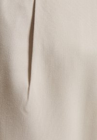 Beige fabric with a smooth texture, featuring subtle vertical pleats. The material appears lightweight and finely woven.