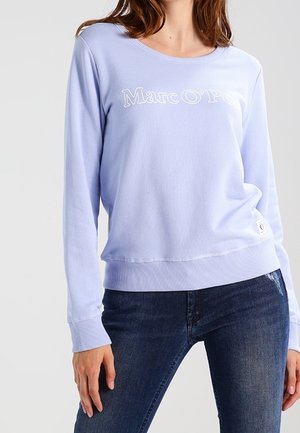 Sudadera de color púrpura claro con cuello redondo, puños y dobladillo acanalados. Presenta un logotipo bordado, textura suave y forma relajada.