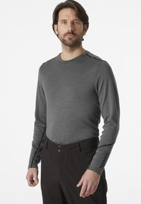 Grijze thermoshirt met lange mouwen van textuurstof, ronde hals, zwarte stiksels en donkere randafwerking bij de manchetten. Draag het met zwarte broek.