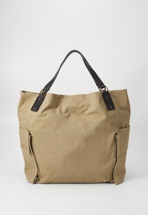 Sac fourre-tout en toile de couleur kaki avec des accents en cuir noir, doté d'un grand compartiment ouvert et d'une poche latérale avec une fermeture éclair.
