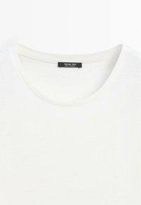 T-shirt blanc à col rond avec étiquette noire Massimo Dutti cousue à l'intérieur du col, fabriqué au Cambodge.