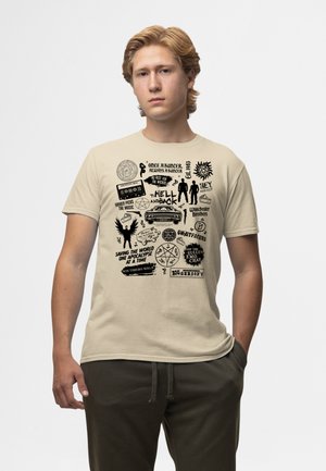 Beige katoenen t-shirt met zwarte grafische tekst en illustraties, waaronder symbolen, citaten en figuren, in verschillende lay-outs en maten.