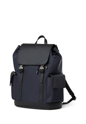 Navy blue backpack with black flap, side pockets, front straps with silver buckles, and a top carrying handle.
