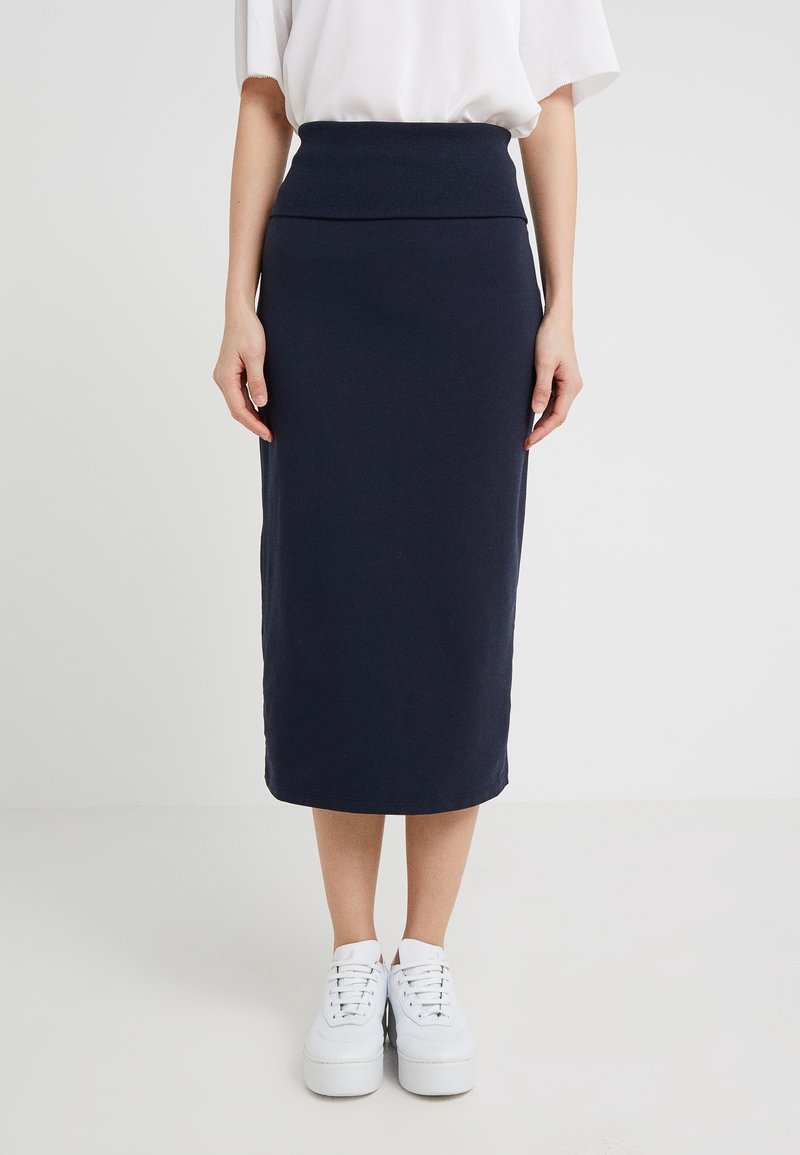 Navyblauwe midi-rok gemaakt van zachte stof, met een brede geribbelde tailleband en een rechte pasvorm. Gekoerst met witte platform sneakers.