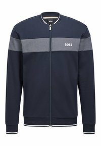 Marinblå zip-up jacka med grå horisontell rand, ribbad krage, ärmar och nederkant, med "BOSS"-logotypen på bröstet. Mjuk tygtextur.