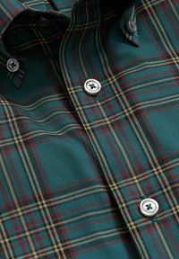 Groene geruite stof met dunne rode en gele strepen, voorzien van chroomknopen en een gladde textuur. Opvallend ruitpatroon zichtbaar.