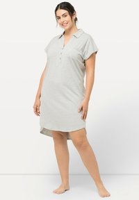 Vestido de polo de algodón gris con mangas cortas, tapeta de botones y un bolsillo en el pecho. Presenta un dobladillo curvado y un corte relajado, llegando a mitad del muslo.