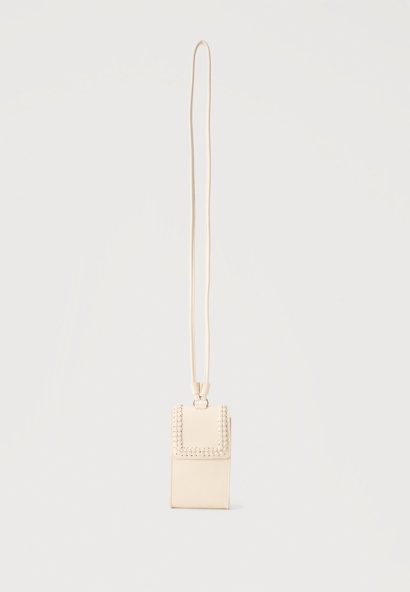 Petit sac besace rectangulaire beige avec détails de bordure tressée et longue bandoulière fine sur un fond uni.