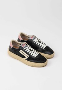 Sneaker in pelle nera con finitura testurizzata e suola beige. Presenta lacci bianchi, dettagli rosa sul tallone e un logo.