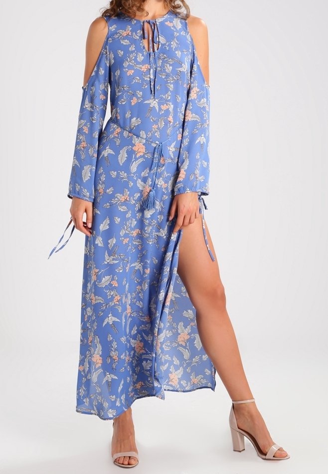 Robe maxi bleue à fleurs avec épaules dénudées, manches longues et fente sur le côté. Le tissu est léger et présente des motifs roses et verts.
