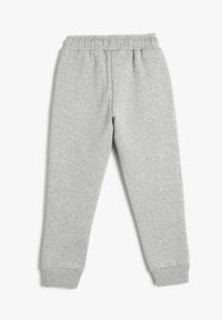 Graue Jogginghose aus weichem Stoff mit einem elastischen Bund und gerippten Bündchen. Glatte Textur ohne sichtbare Muster oder Hardware-Details.