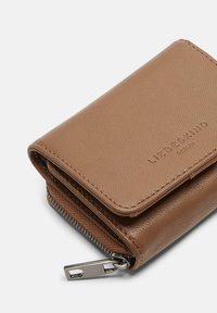 Kompakte braune Geldbörse aus Leder mit gesteppten Kanten, geprägtem Markennamen und einem silbernen Reißverschlussanhänger auf weißem Hintergrund.