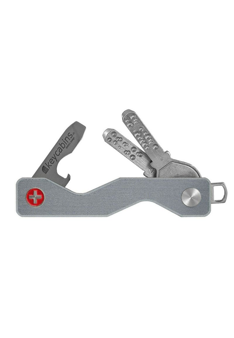 Metal key holder with a flat, curved design, featuring a red Swiss cross emblem, a bottle opener, and multiple gray keys.