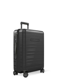 Black hardshell suitcase with a sleek design, ribbed texture, retractable handle, and four wheels for mobility. Features a combination lock.