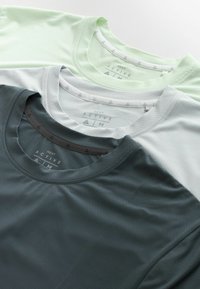 Kolm voltimist meeskonnakaelusega spordipluusi helerohelises, helehallis ja tumehallis, mis on kaldus virnas valgel pinnal.