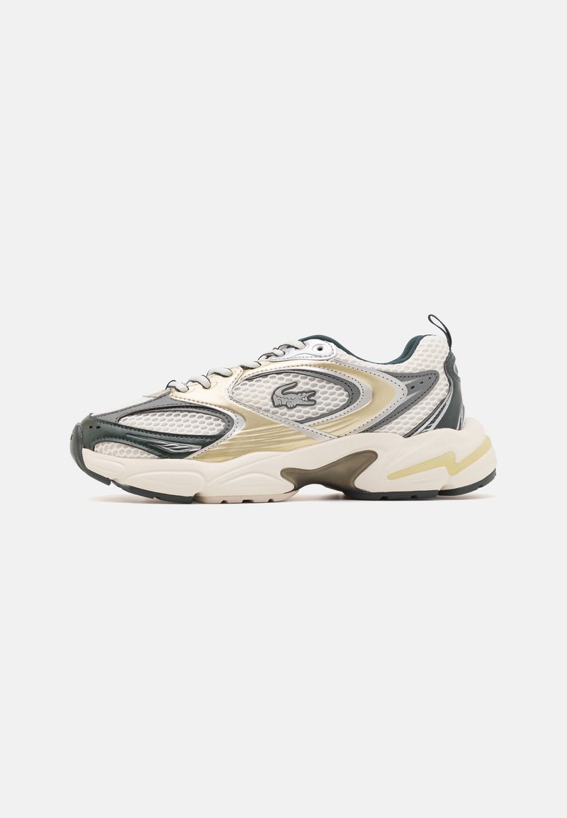 Baskets de sport avec des panneaux en mesh et synthétique blanc, beige et vert foncé, semelle épaisse et petit logo crocodile sur le côté.
