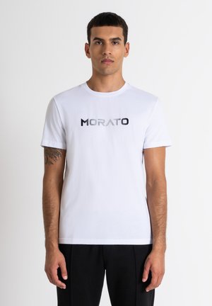 Camiseta de algodón blanca con la palabra "MORATO" en una fuente degradada de negro a gris en el pecho. Mangas cortas, cuello redondo.