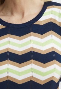Pletený top s vzorem chevron v námořnické modré, béžové, zelené a bílé barvě. Kulatý výstřih s texturovanými švy.