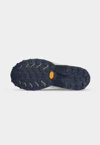 Semelle de chaussure avec des crampons profonds multidirectionnels et un logo jaune Vibram central pour une meilleure adhérence et durabilité sur terrain accidenté.