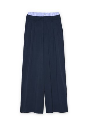 Pantalones de pierna ancha azul marino con pliegues y trabillas para cinturón, con un detalle de cinturilla a rayas azules y blancas.