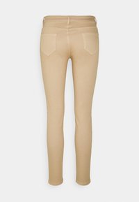 Beige slim-fit-housut, joissa on takataskut ja vyölenkit, näkyvät takaa, tasaisen valkoisen taustan edessä.