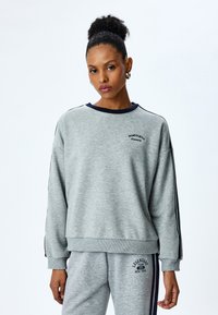 Grijze sweatshirt met een marineblauwe kraag en zijstrepen, met daarop "Washington" geborduurd op de borst. Casual, relaxte pasvorm.
