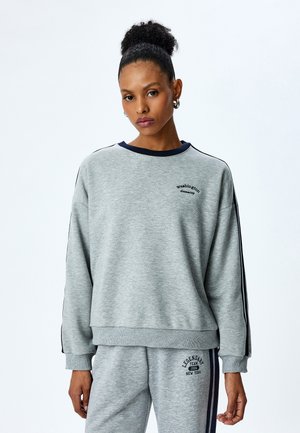 Sudadera gris con cuello marino y franjas laterales, con "Washington" bordado en el pecho. Corte casual y relajado.
