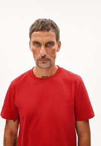 Rode katoenen T-shirt met korte mouwen, ronde hals en een gladde textuur. Eenvoudig ontwerp zonder zichtbare logo's of patronen.