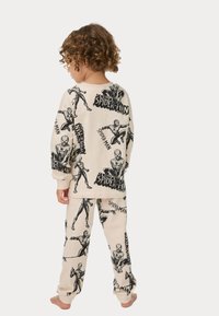 Ensemble de pyjama beige pour enfants avec un imprimé Spider-Man intégral. Fabriqué en tissu doux avec des manches longues et une taille élastique. Les motifs comprennent des poses d'action.